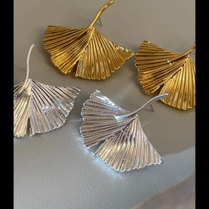 Macro view of gold and silver ginkgo leaf earrings with detailed metallic textures
