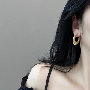 Fashionable gold woven texture C-shaped chunky hoop earrings worn by a model