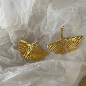 Detailed view of golden ginkgo leaf earrings with fine radial texture and metallic finish