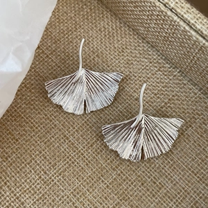 Detailed view of silver ginkgo leaf earrings featuring fine radial texture and metallic finish