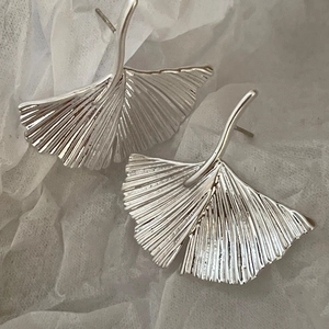 Detailed macro view of silver ginkgo leaf earrings with delicate radial vein texture