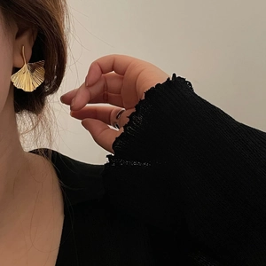 Exaggerated gold ginkgo leaf stud earring with realistic leaf texture on female model