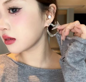 Close-up of double layered hollow heart hoop earrings worn by a model for size display