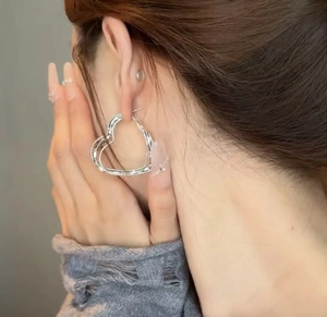 Close-up of a model wearing stylish silver heart-shaped hoop earrings for a trendy look
