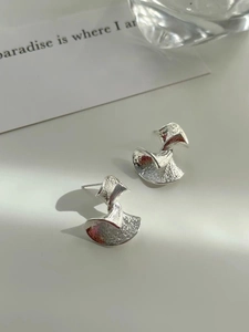 Detailed view of silver twist fan earrings with textured surface and abstract geometric design