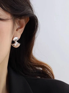 Detail of silver twisted earrings with hammered texture on a model side profile