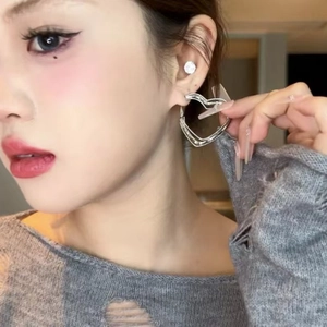 Silver hollow heart-shaped layered hoop earrings worn by a model in close-up view