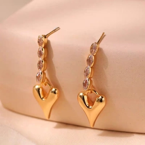 Détail de boucles d'oreilles pendantes plaquées or 18K avec zircons et pendentif coeur