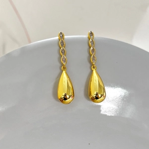 Détail macro de longues boucles d'oreilles pendantes en or 18K avec zircons et gouttes