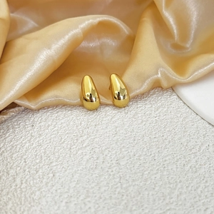 Polished gold teardrop earrings for women on elegant champagne silk background
