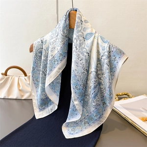 Elegant blue and white paisley silk square scarf displayed on a wooden hanger