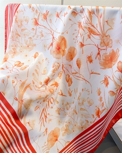 Close-up of floral silk scarf with vibrant orange prints and red striped edges