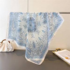 Elegant blue and white paisley print square silk-feel scarf draped on a display stand