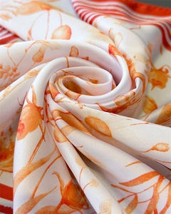 Detailed view of white silk scarf with pomegranate floral prints and red stripe border