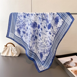 Detail of blue floral silk scarf showing elegant drape and smooth satin texture on rack