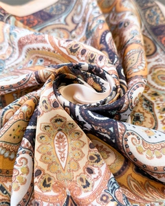 Detail of elegant paisley silk-like scarf with orange and beige draped patterns