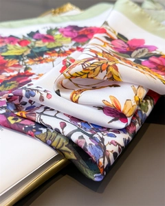 Close-up of floral print satin scarf with green edges and soft silky fabric texture