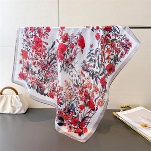 Elegant floral silk square scarf with red and blue patterns hanging by a stylish handbag