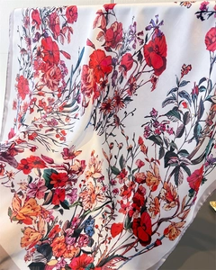 Close-up of floral print silk scarf featuring vivid red and orange flowers on white fabric