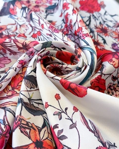Detailed macro view of spiral-folded silk scarf featuring colorful floral print patterns
