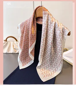 Detailed close-up of orange and cream silk scarf featuring repetitive letter D pattern