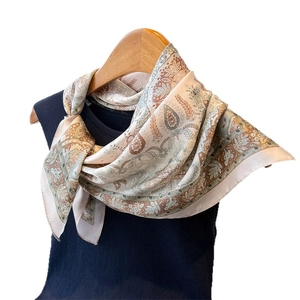 Elegant paisley print silk-like scarf tied on a hanger with blue knit sweater