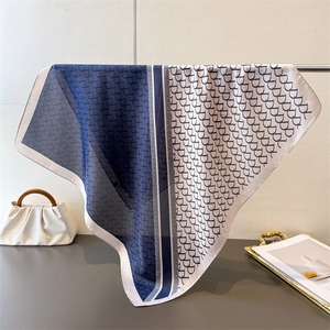 Detail of silk-like square scarf featuring gradient blue shades and monogram patterns