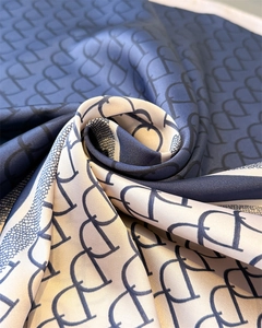 Detailed view of navy and cream silk scarf featuring a classic monogram pattern