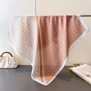 Detail of silk square scarf featuring orange-pink geometric horse hoof patterns and drape