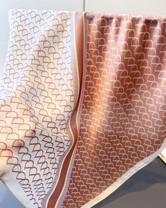 Detail of silk texture and geometric monogram pattern on orange-pink square scarf