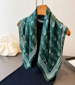 Detail eines dunkelgrünen Seidenschals mit Paisleymuster auf Holzkleiderbügel