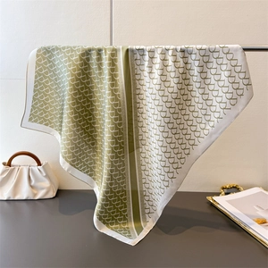 Detail view of draped olive and ivory silk scarf with geometric horseshoe pattern on rack