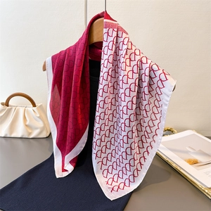 Detailed close-up of burgundy and white silk scarf with vintage monogram pattern