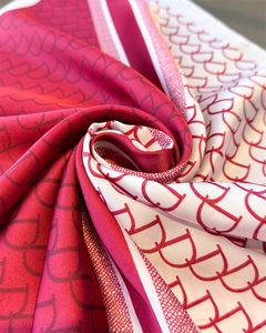Detailed macro view of the soft satin texture and CD logo pattern on the silk scarf