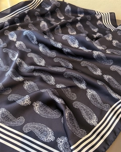 Detailansicht eines dunkelblauen Satinschals mit Paisleymuster und Streifenrand