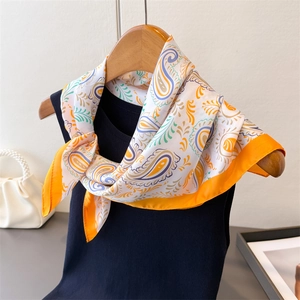 Detailed view of paisley silk-like scarf tied on a hanger showing drape and vibrant colors