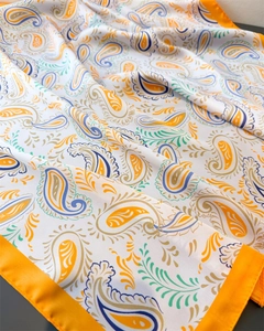 Close-up of silk-feel scarf featuring vibrant paisley prints and orange hem border detail
