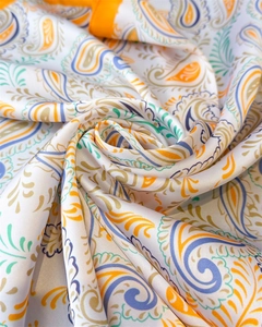 Detailed macro view of paisley pattern silk scarf with vibrant orange rolled edges