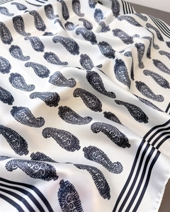 Detail eines seidigen quadratischen Tuches mit schwarzem Paisleymuster und Streifen
