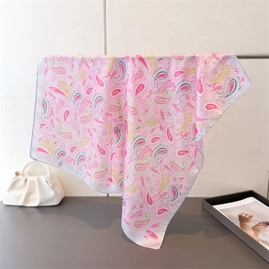Detailed close-up of pink paisley silk scarf with satin texture and white rolled edges