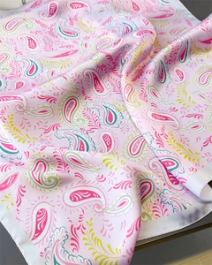 Detail of pink paisley silk scarf fabric showing smooth texture and draped edges