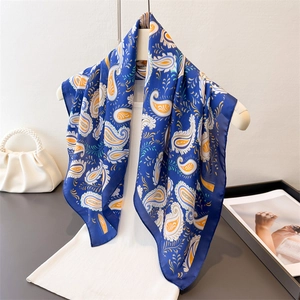 Deep blue paisley silk scarf with orange patterns displayed on a fashion mannequin