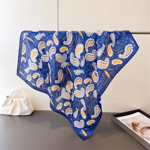 Detail of blue paisley silk scarf draped over a stand next to a white pearl handle bag