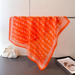 Detail eines luxuriösen orangefarbenen Satin-Vierecktuches mit Paisley-Muster auf Metallstange