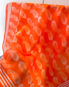 Detailansicht eines hellorangen Seidenschals mit Paisley-Muster und elegantem Faltenwurf