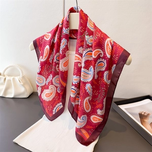 Elegant red paisley silk scarf displayed on a white dress with classic French styling