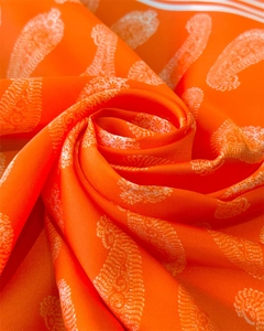 Detail eines orangefarbenen Seidenschals mit Paisley-Muster und weißen Randstreifen