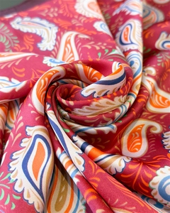 Close-up of pink silk-like scarf with vibrant paisley pattern and satin finish