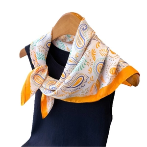 Elegant silk-like scarf with orange paisley print on black sleeveless shirt