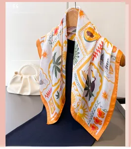 Detail of tropical print silk scarf with palm trees and orange border on wooden hanger